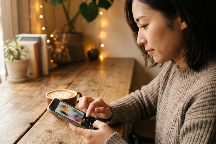 カフェのようなリラックスした空間でスマホアプリを操作している日本人女性