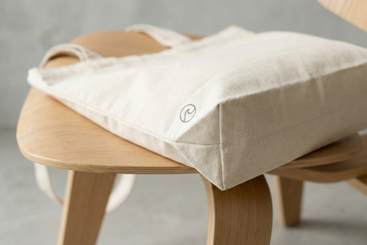 トートバッグの右下に小さくロゴが配置された、高級感のある置き画（クローズアップ）