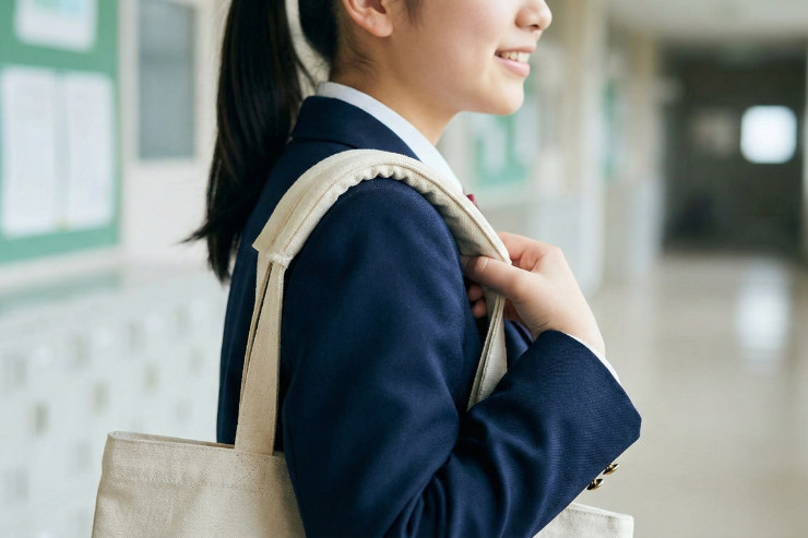 トートバッグを肩にかけ、持ち手の長さを確認している日本の女子学生